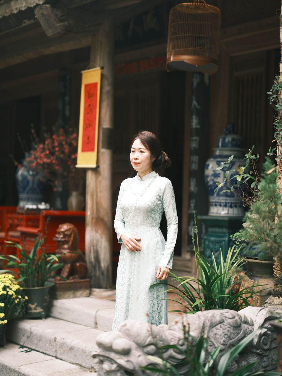 Vietnamese woman in ao dai standing gracefully in a cultural setting.
