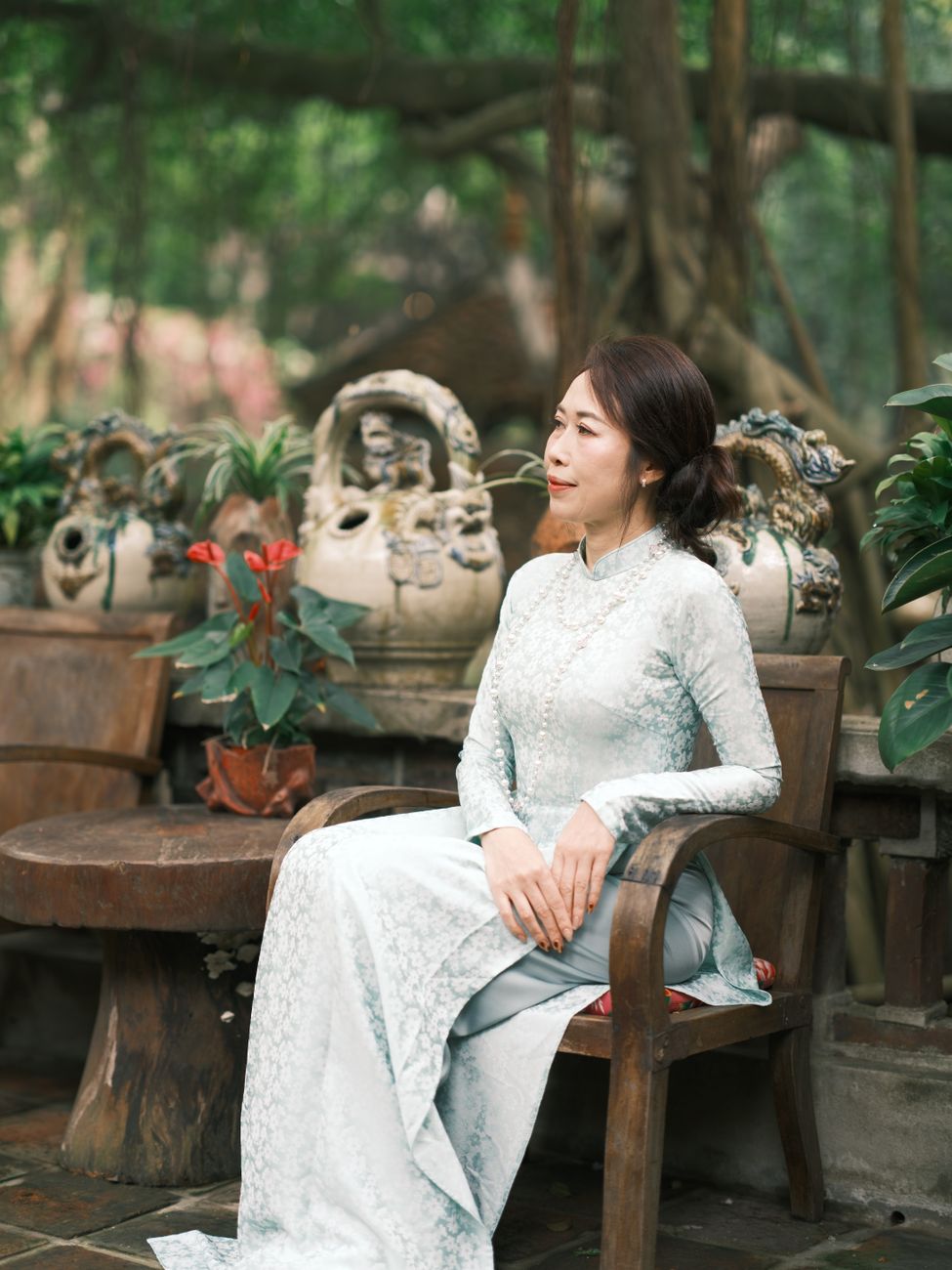 A serene portrait of a woman wearing a traditional white Ao Dai in a lush garden setting in Vietnam.