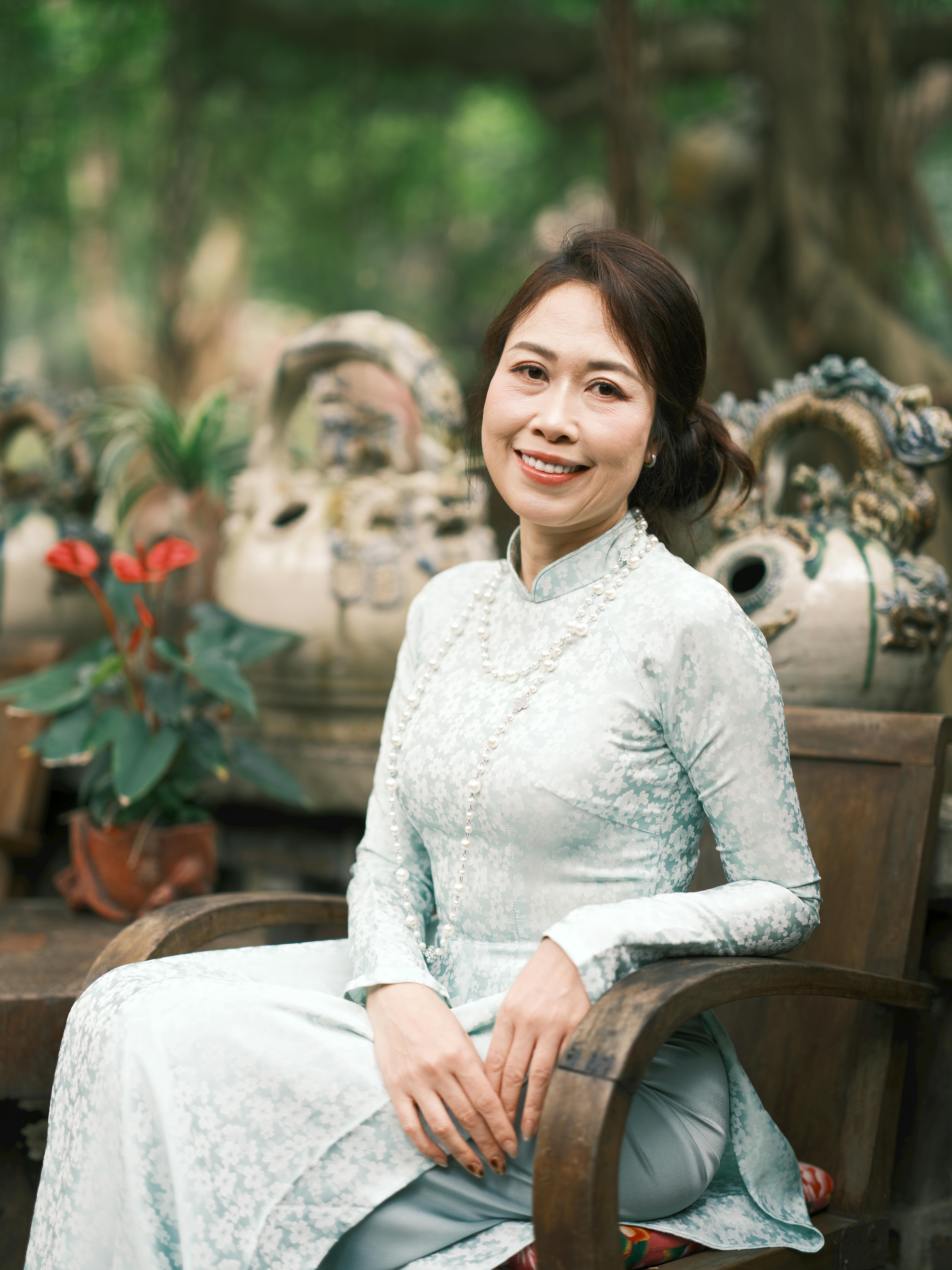 Smiling woman in traditional Vietnamese Áo Dài, seated outdoors in Việt Nam