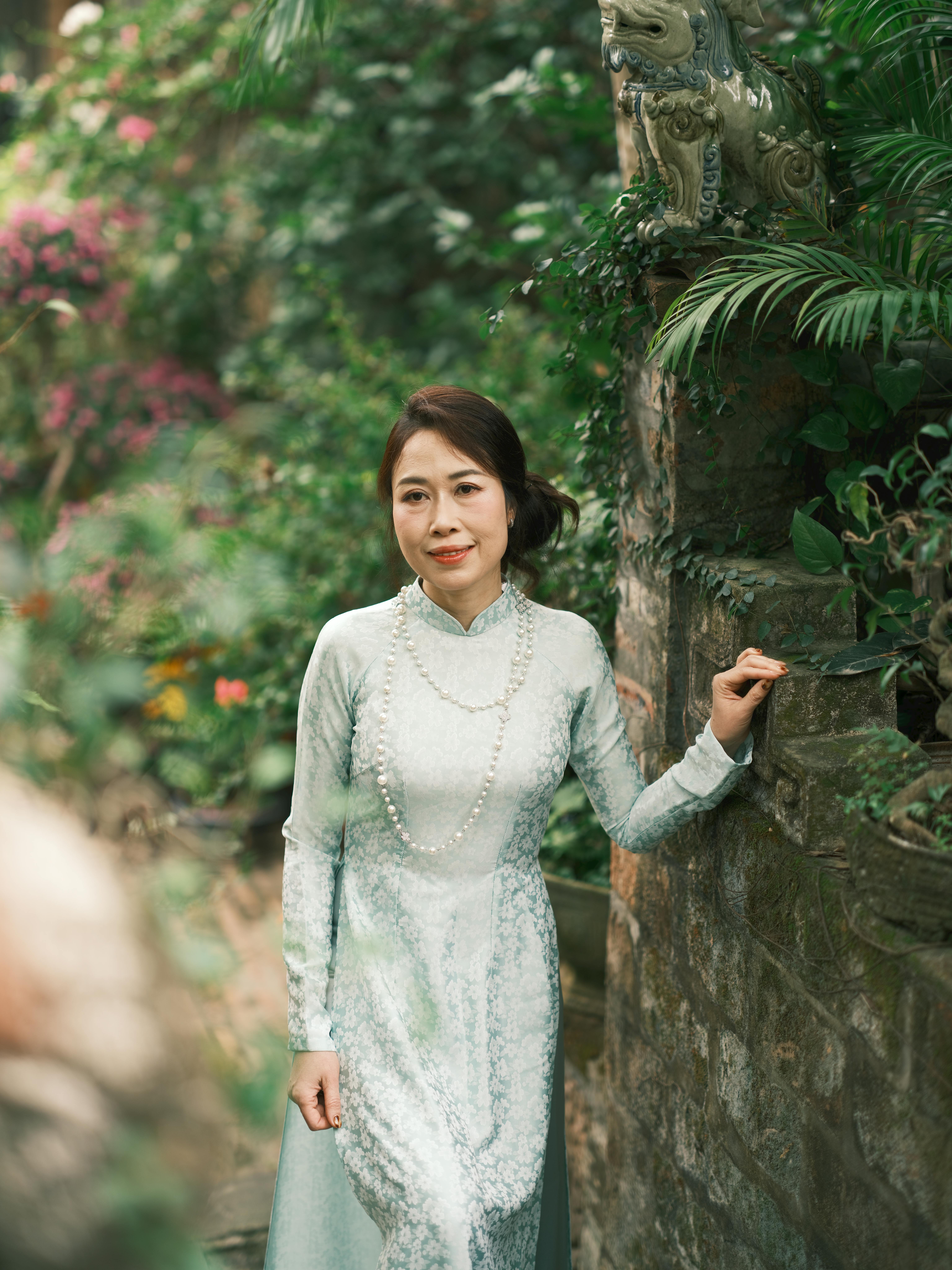 A woman in traditional Vietnamese attire poses gracefully in a lush garden.