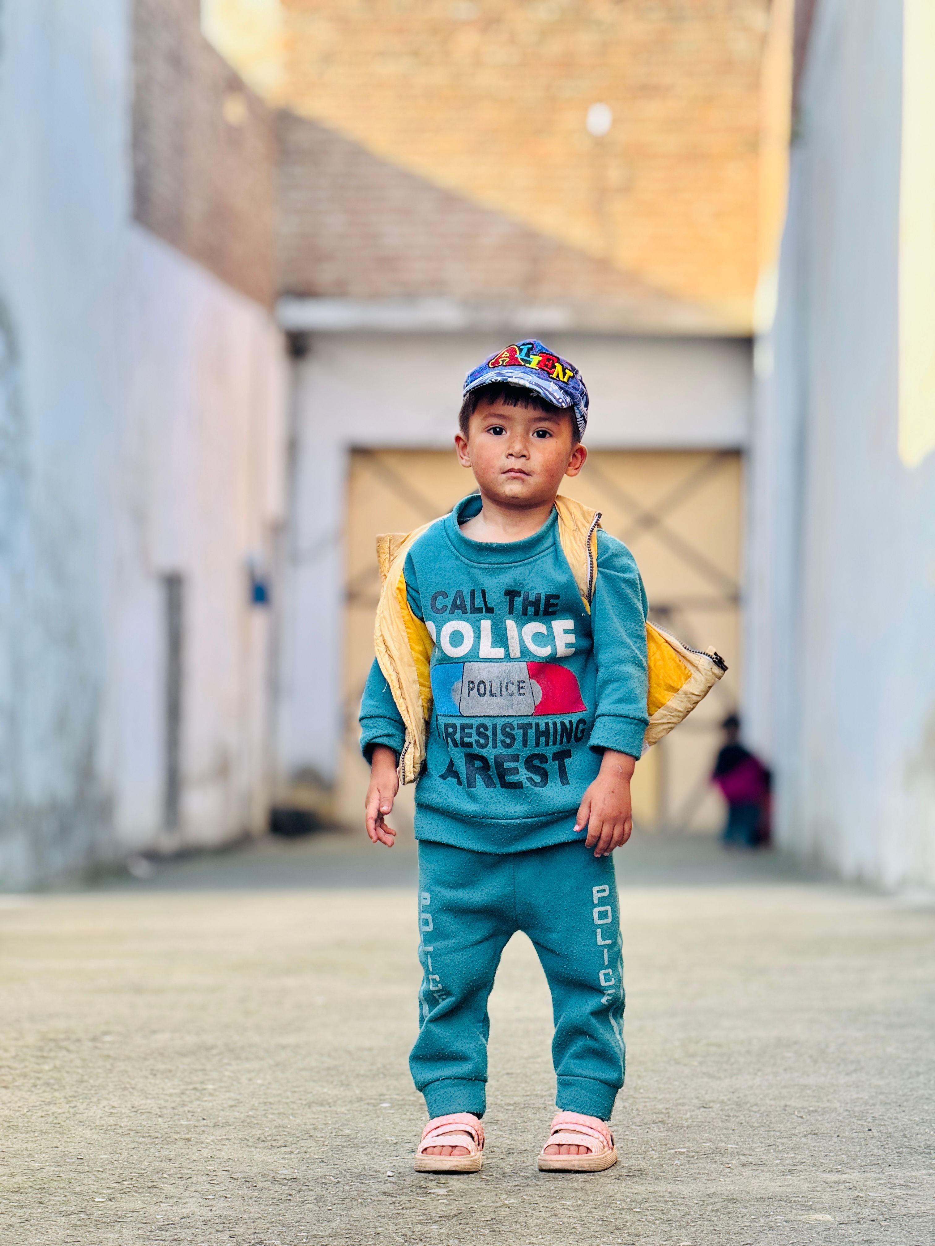 A young child stands confidently in vibrant attire outdoors, showcasing playful clothing and attitude.