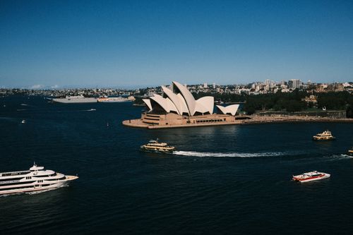 Free A breathtaking aerial view capturing the iconic Sydney Opera House surrounded by ferry boats on a sunny day. Stock Photo