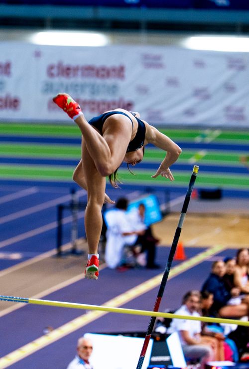 Free Dynamic capture of a female athlete mid-pole vault inside an indoor sports facility. Stock Photo