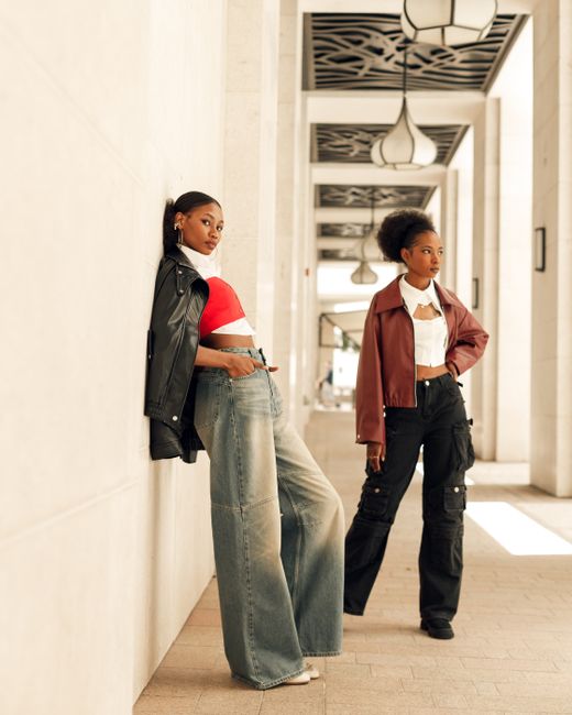 Fashion-forward photo of two models showcasing urban style in a modern architectural setting.
