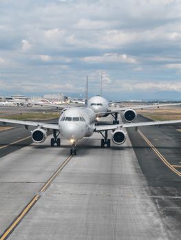 Two commercial airplanes lined up on the runway ready for takeoff at Pasay City airport in the Philippines.