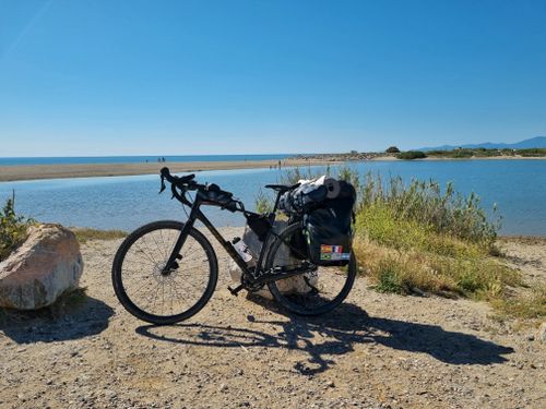 Kostnadsfria Cykel med reseutrustning på en naturskön kuststig i Frankrike under en klarblå himmel. Stock foto