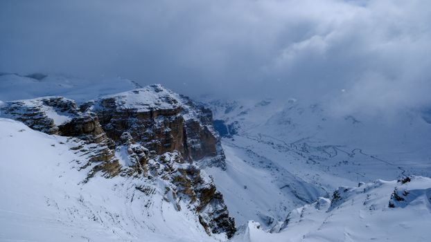 Snow-covered alpine mountains with rugged cliffs and a moody sky in the Dolomites.