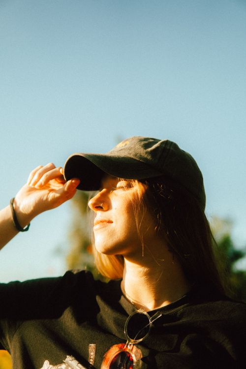 Free Portrait of a young woman wearing a cap enjoying the sunshine outdoors in Sete Lagoas, MG. Stock Photo