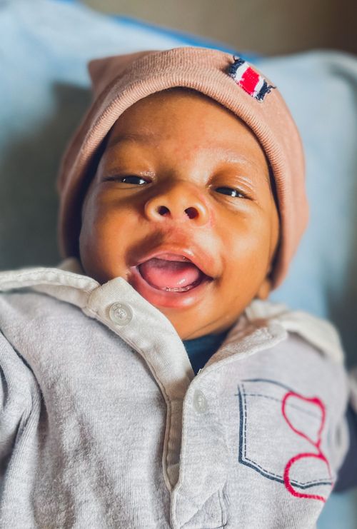 Free A smiling baby in a warm onesie and hat, expressing joy and comfort. Stock Photo