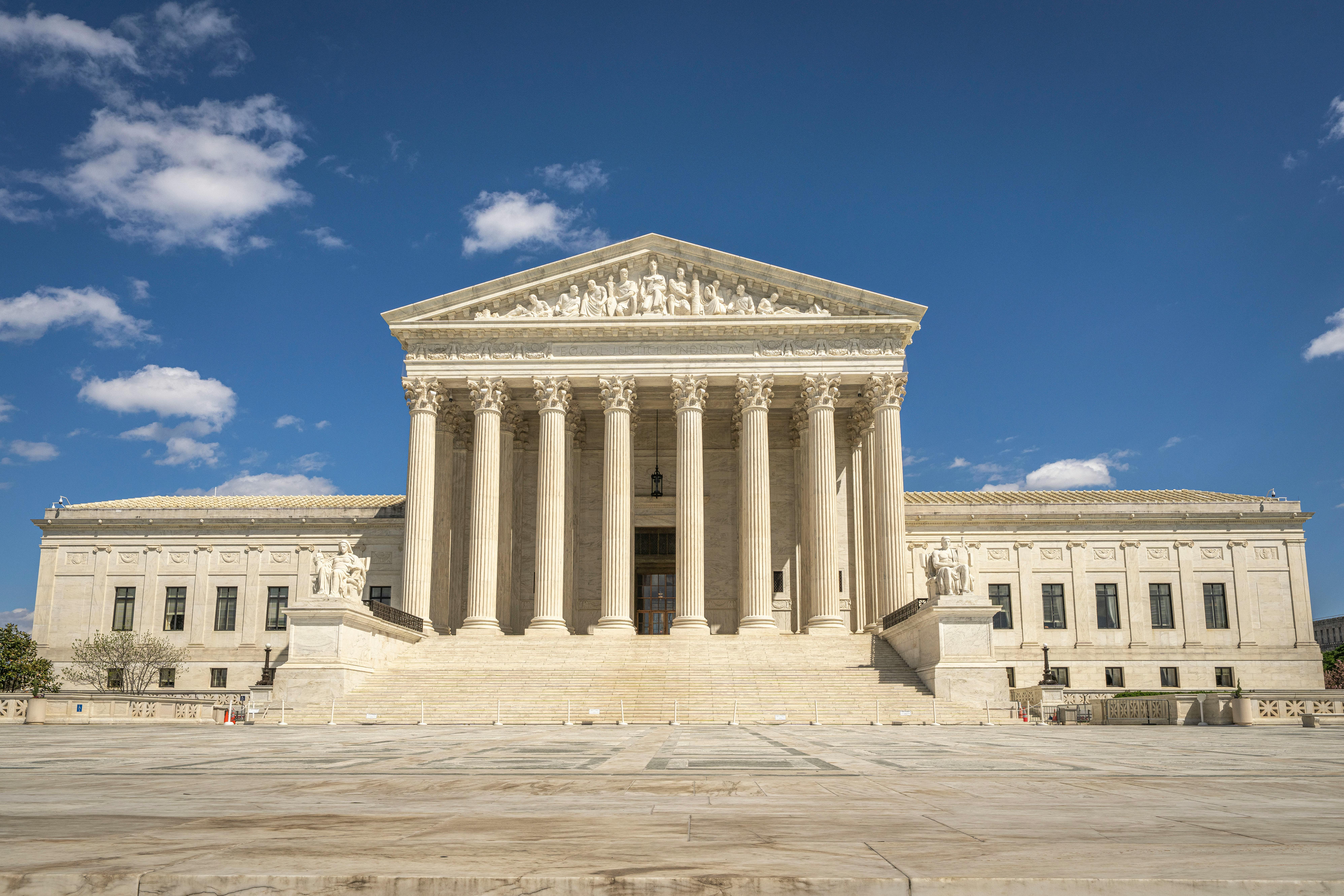 The majestic facade of the United States Supreme Court under a clear blue sky. | BocaVibe