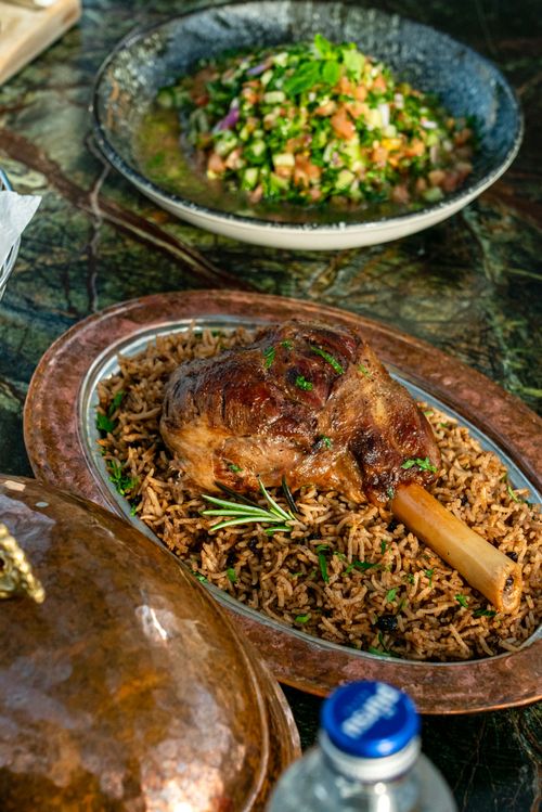 Free Savor a roasted lamb shank on aromatic rice with a fresh side salad in the background. Stock Photo