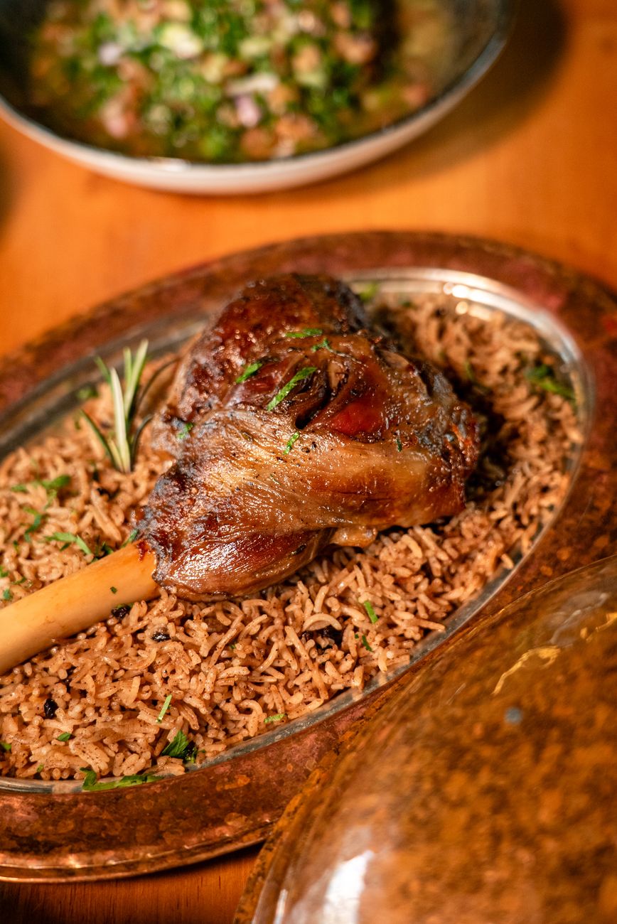 Savory lamb shank served on flavorful spiced rice, garnished with rosemary.