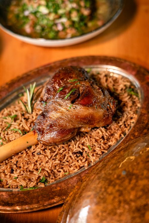 Free Savory lamb shank served on flavorful spiced rice, garnished with rosemary. Stock Photo