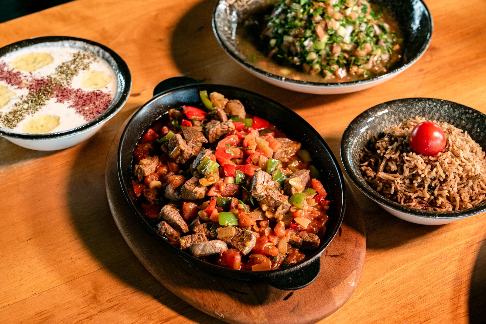 A delicious spread of Middle Eastern dishes featuring meats and rice on a wooden table.