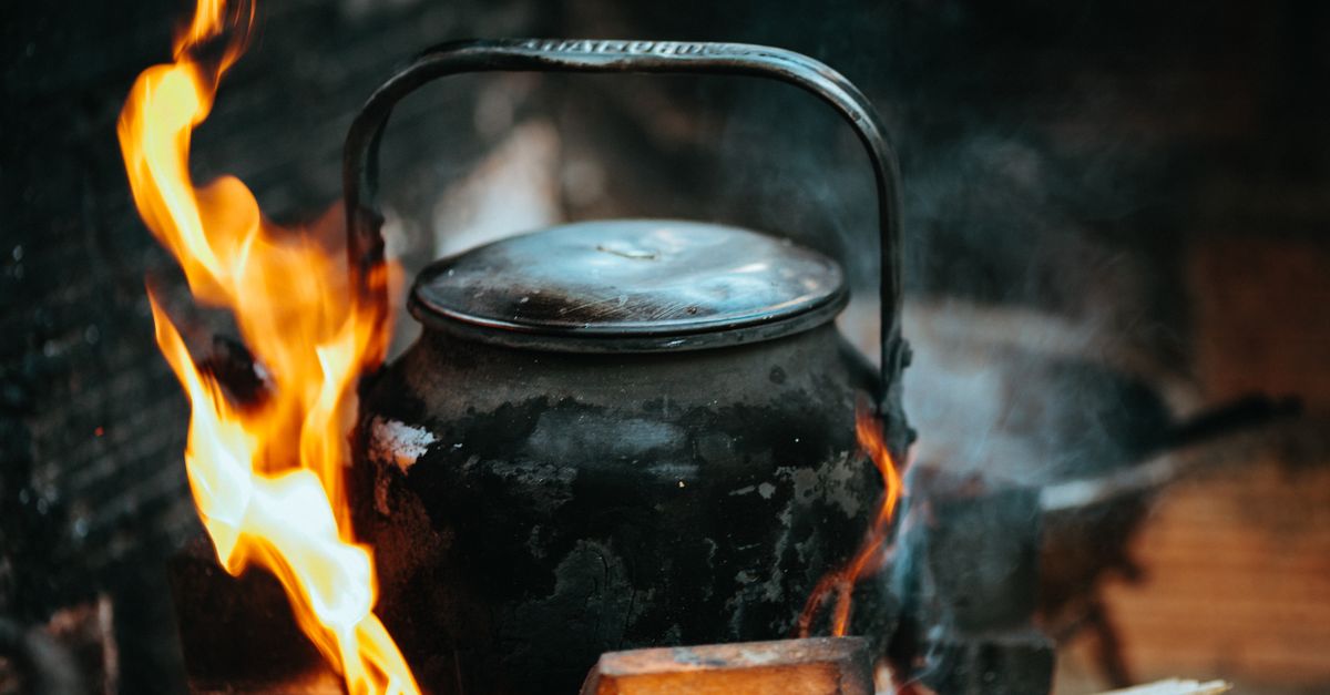 A rustic kettle with fire and smoke, depicting traditional Vietnamese cooking outdoors.