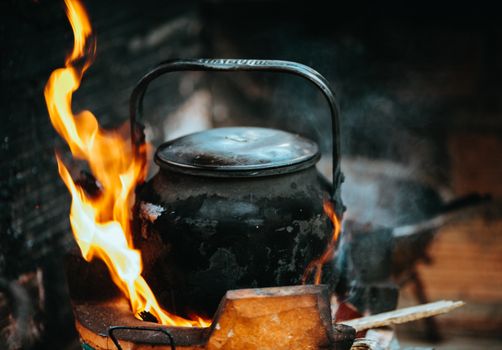 A rustic kettle with fire and smoke, depicting traditional Vietnamese cooking outdoors.