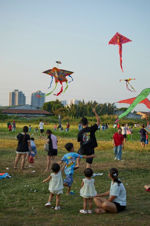 Free Families enjoy flying kites in a vibrant park setting in Ho Chi Minh City, Vietnam. Stock Photo