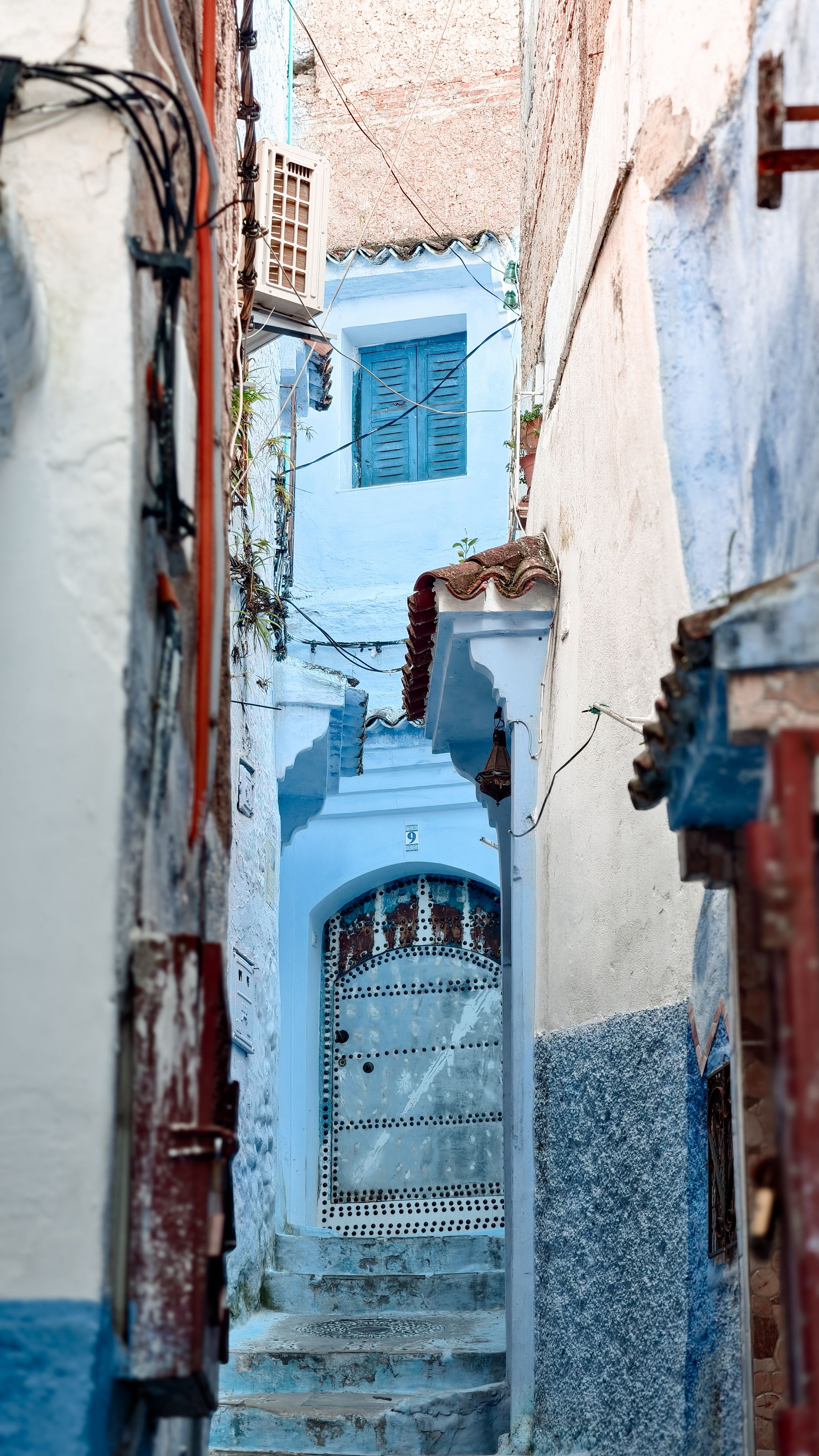 Fotomural Un pintoresco callejón en Chefchaouen, que exhibe los emblemáticos edificios azules y una arquitectura detallada.