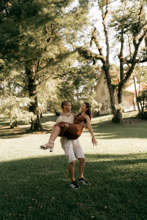 Free Happy couple in summer attire enjoying a playful moment in a sunlit garden. Stock Photo