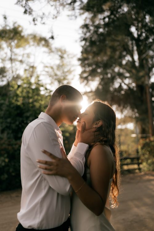 Free A couple sharing a tender moment outdoors during sunset, creating a romantic and warm atmosphere. Stock Photo