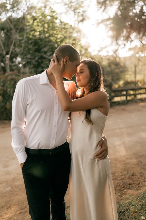 Free A young couple sharing an intimate moment on a sunlit path, capturing love and romance outdoors. Stock Photo