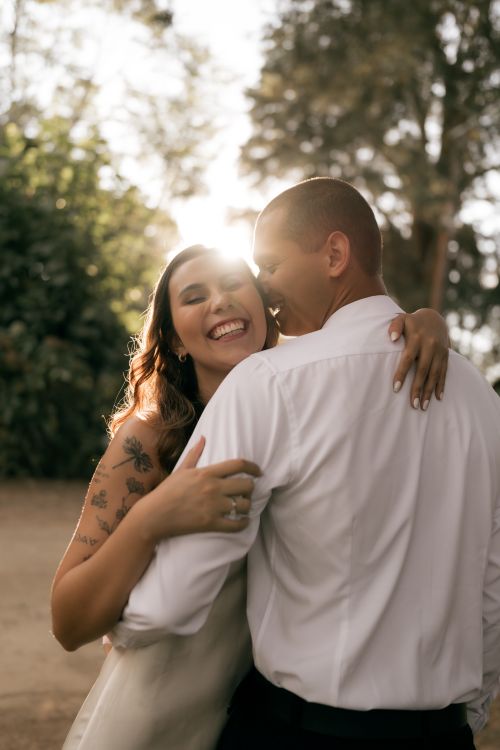 Free Happy couple embracing outdoors with sunflare, conveying love and joy in natural setting. Stock Photo