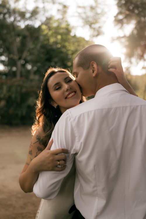 Free A couple shares a loving embrace during a warm sunset outdoors. Stock Photo