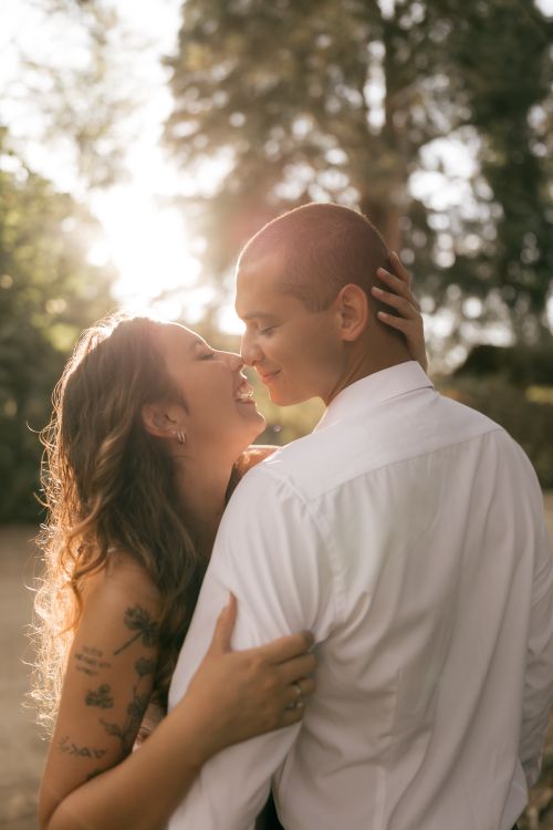 Free A romantic moment captured of a couple embracing in a sunlit outdoor setting. Stock Photo