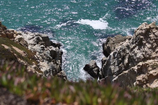 Stunning view of waves hitting rocky cliffs on a sunny day, ideal for coastal and nature themes.