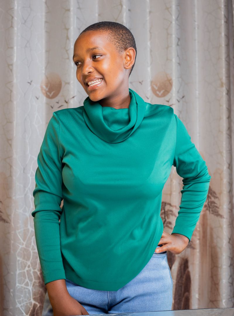 Woman in green turtleneck indoors, cozy professional outfit