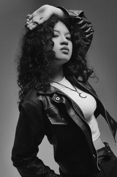 Black and white portrait of a stylish woman in a leather jacket striking a confident pose.