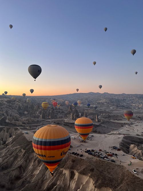 Free A breathtaking view of colorful hot air balloons floating over Cappadocia's unique landscape at sunrise. Stock Photo