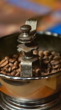 Close-up of a vintage coffee grinder filled with coffee beans, highlighting rustic details.