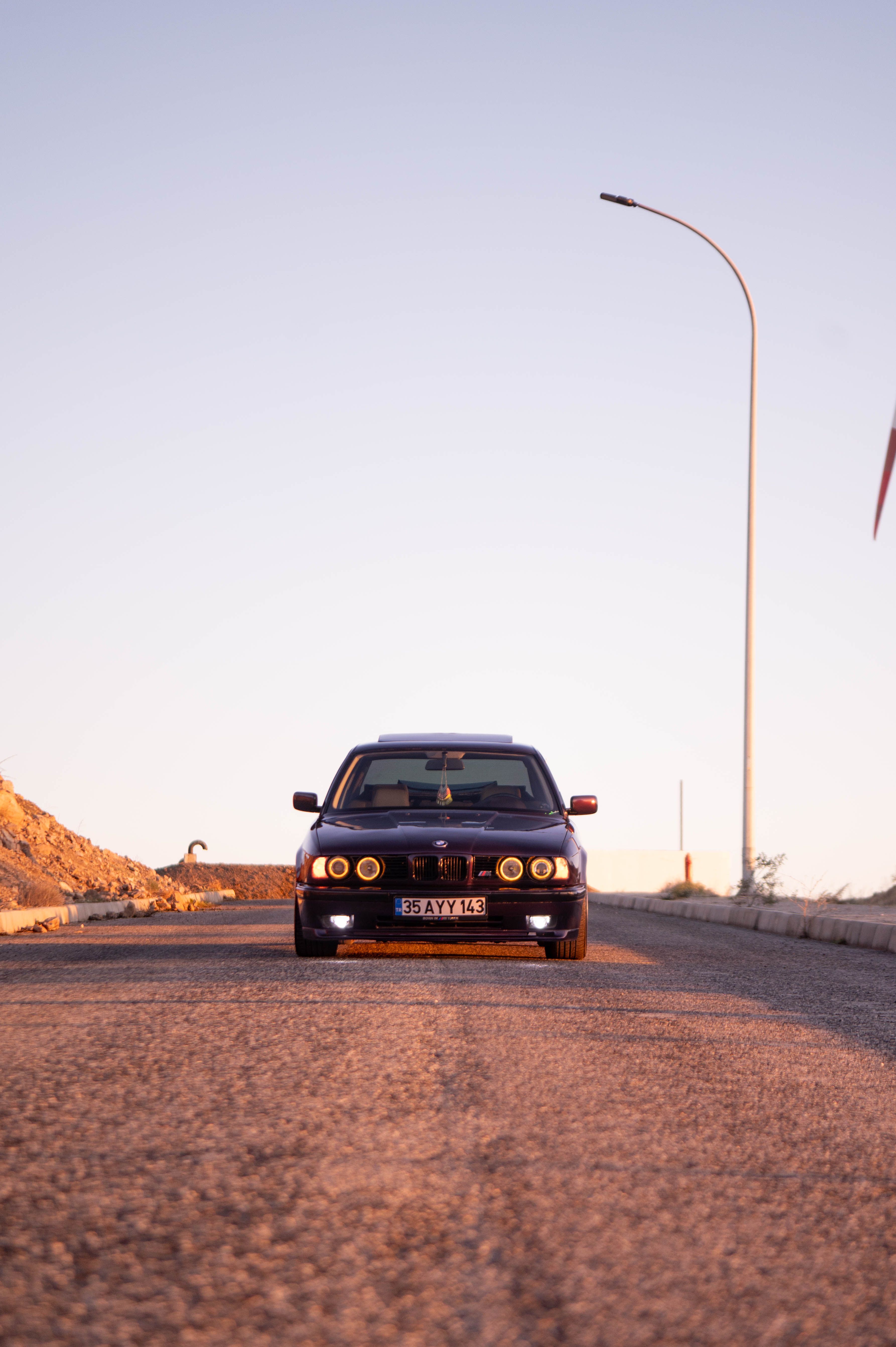 Classic BMW Driving Down Desert Road at Sunset · Free Stock Photo