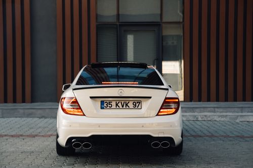 Free Rear view of a Mercedes-Benz C180 W204 parked outdoors with modern architecture backdrop. Stock Photo