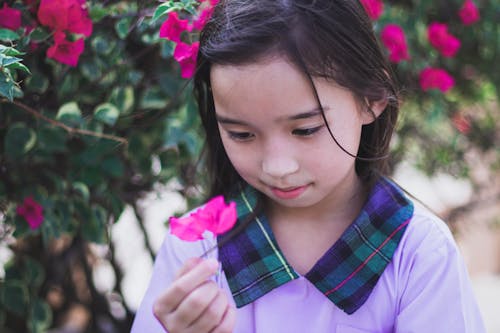 Girl in Pink and Blue Plaid Shirt Holding Pink Flower