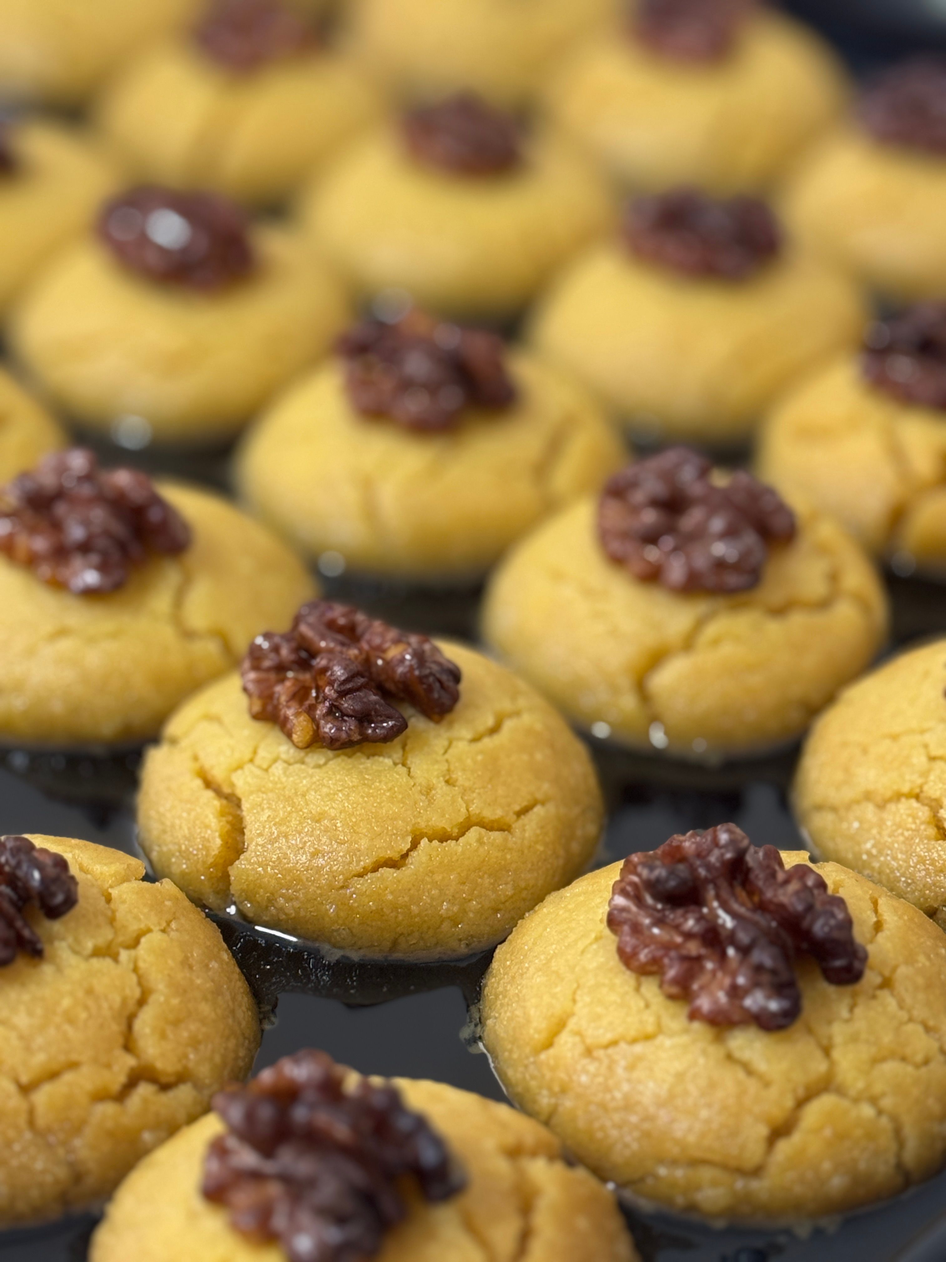 Close-up of Turkish şekerpare cookies topped with walnuts, syrupy and golden brown.