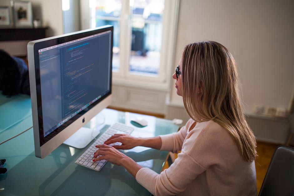 Seated Woman Typing on Apple Mighty Keyboard in Front of Turned-on Silver Imac