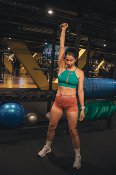A fit woman lifting a kettlebell in a modern gym setting, showcasing strength.