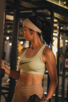 Fit young woman lifting dumbbells indoors, focused on fitness routine in a modern gym.