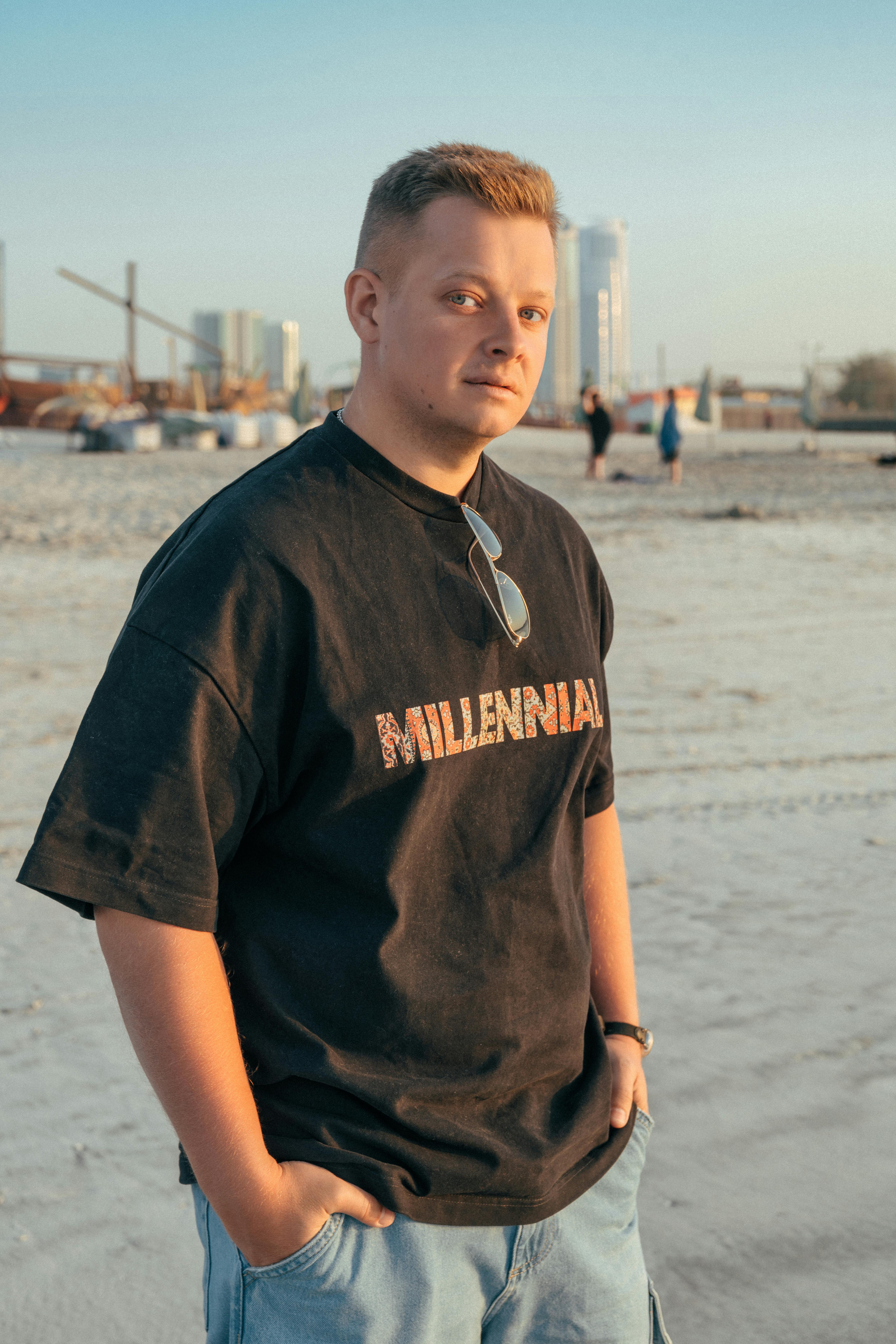 Young man stands on a beach in Sharjah, embodying urban lifestyle.