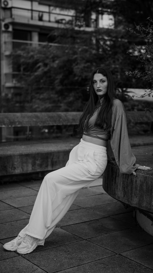 Free Elegant black and white portrait of a woman sitting outdoors, showcasing stylish fashion. Stock Photo
