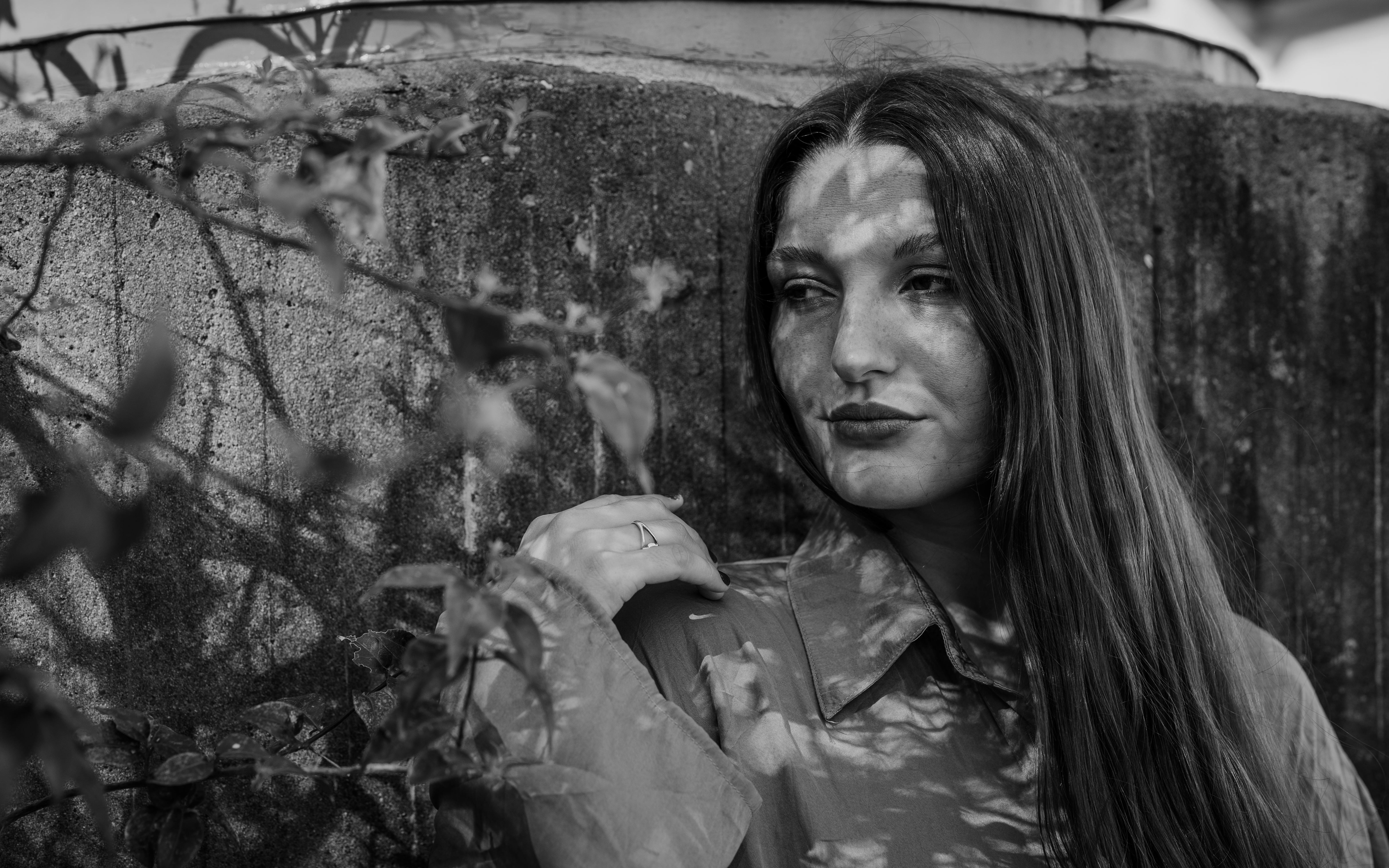 A moody black and white portrait of a woman using shadows of leaves for a dramatic effect.
