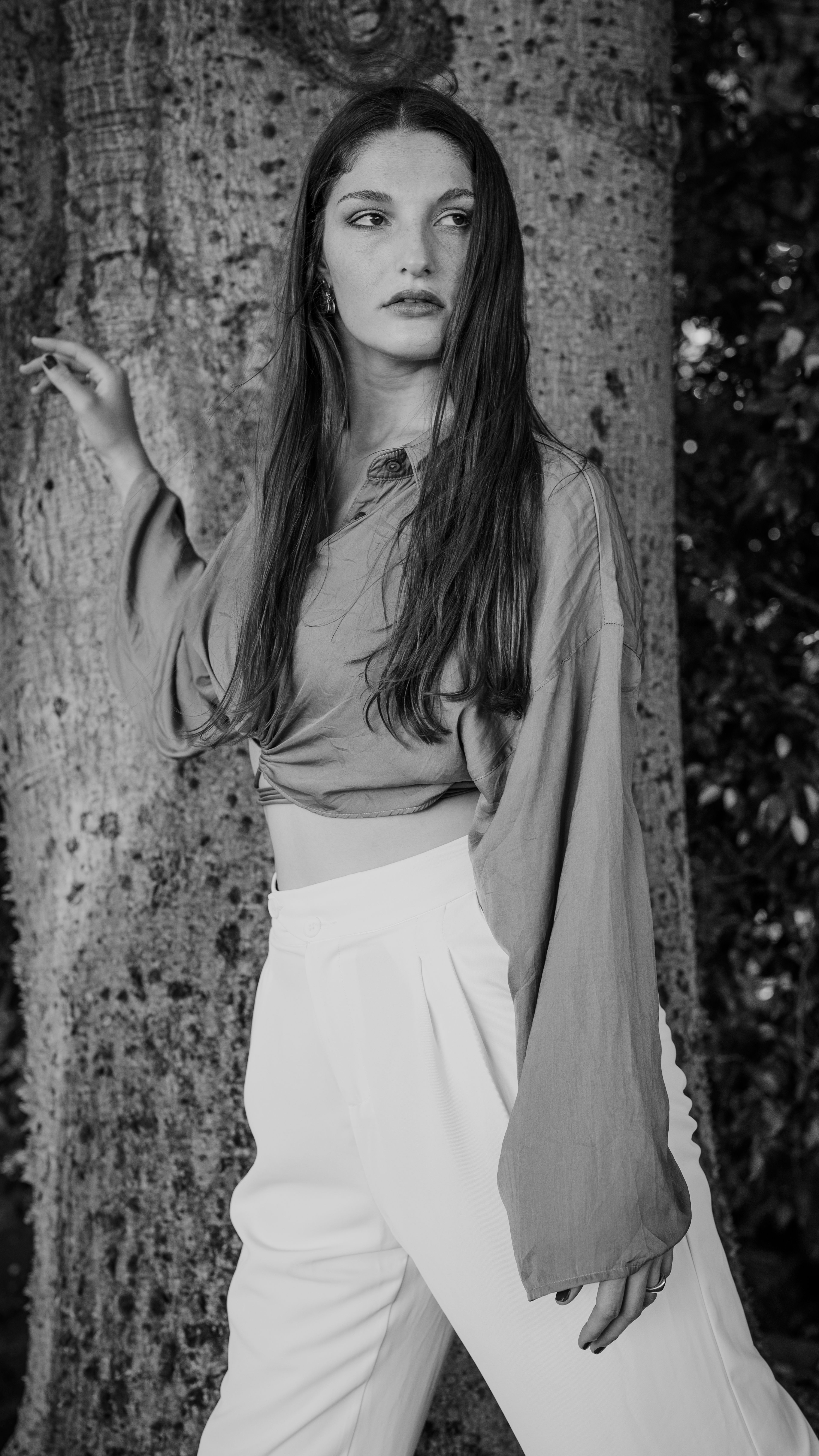 Black and white portrait of a young woman in nature, capturing elegant style.