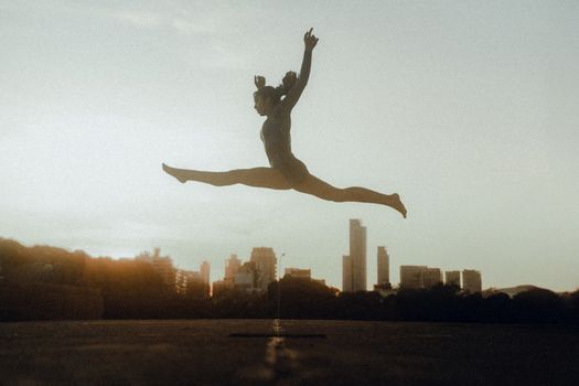 A gymnast executing a leap against the Buenos Aires skyline at twilight.