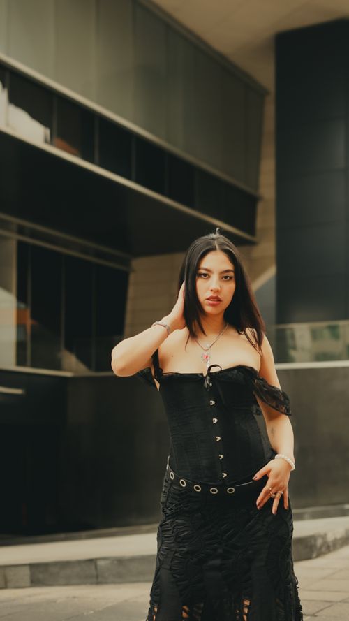 Free Woman in stylish black attire posing in a modern urban environment. Stock Photo