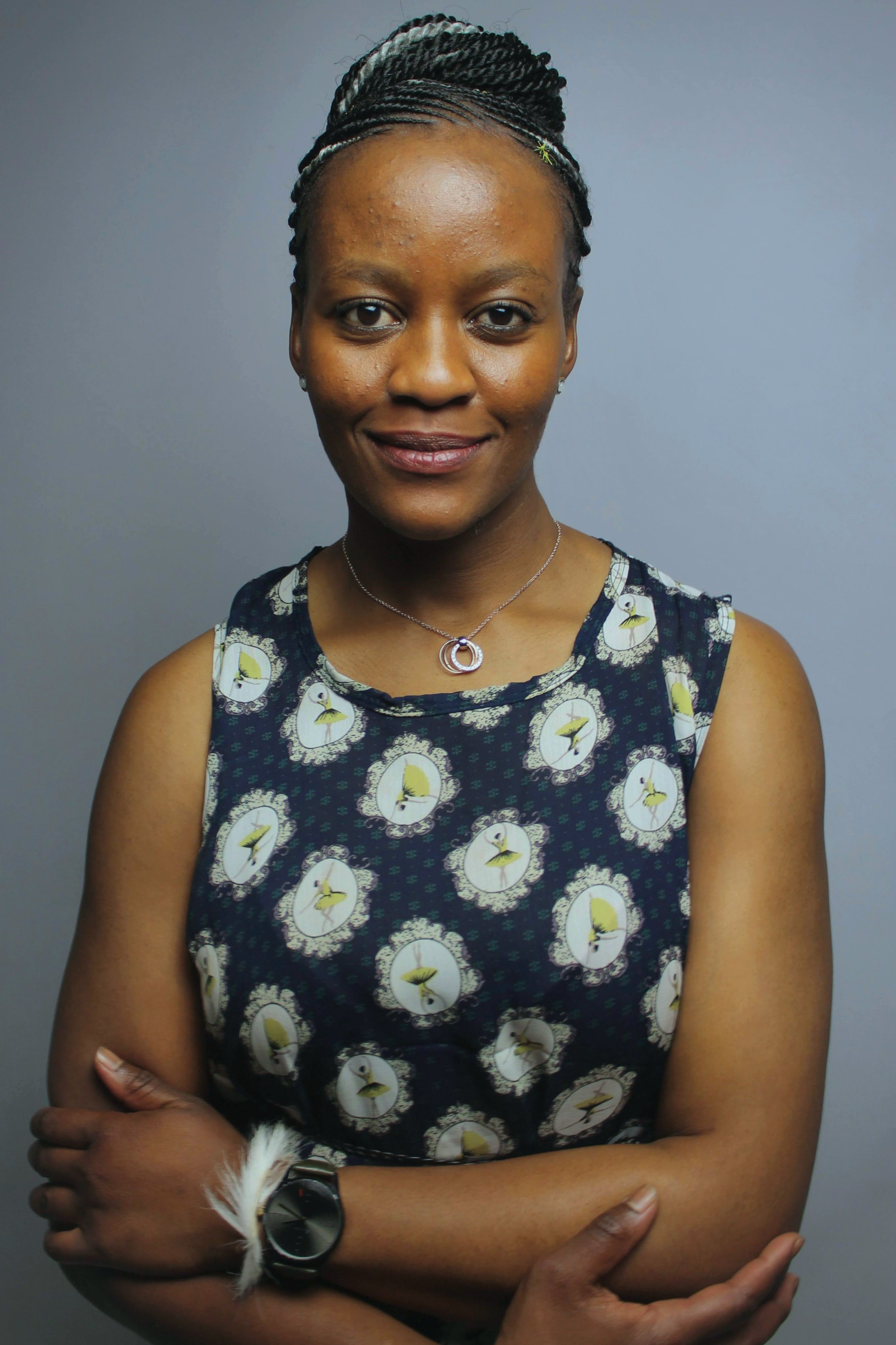 A confident woman with braided hair smiling at the camera in a studio.
