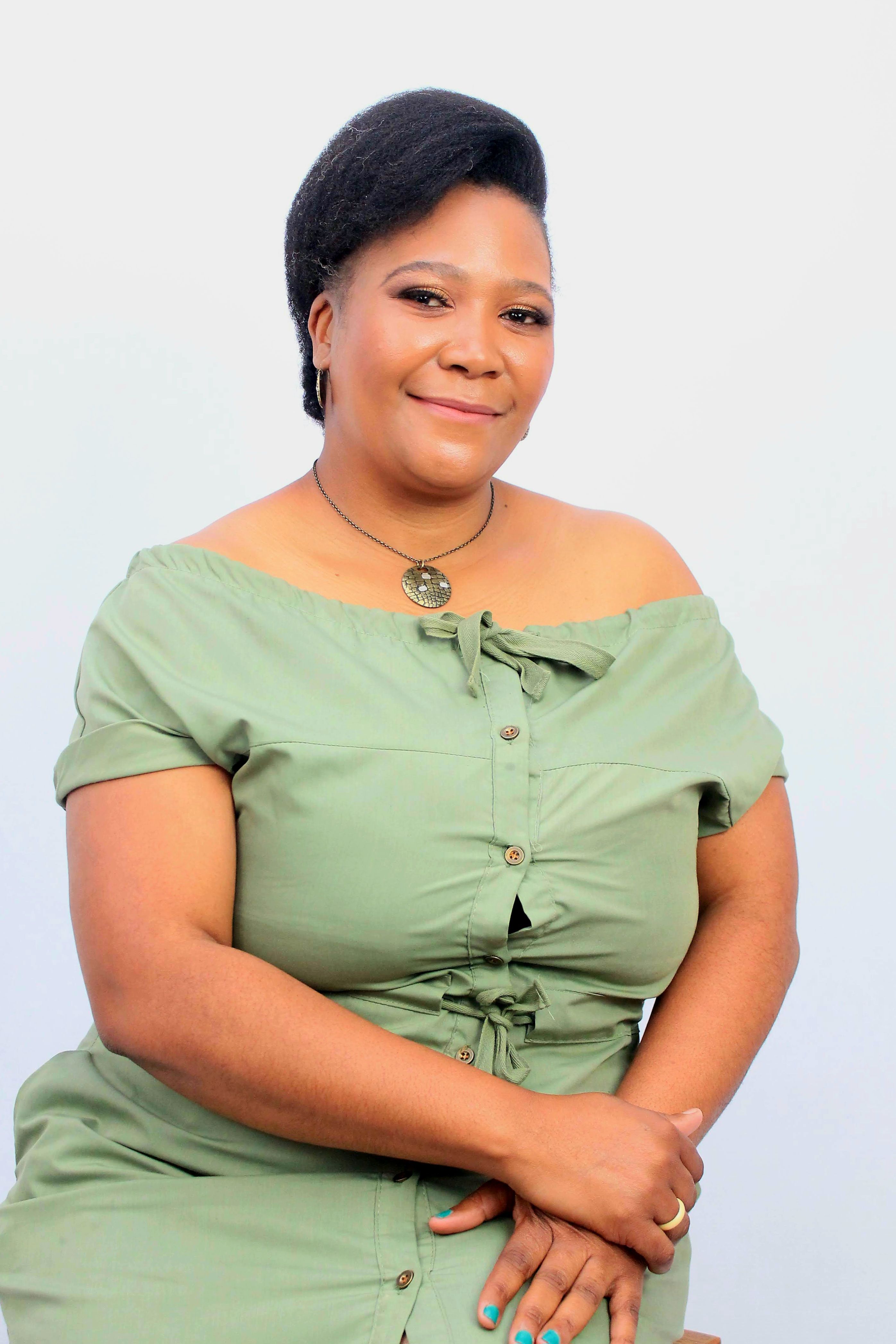Elegant portrait of an adult woman wearing a green dress and necklace, against a neutral background.