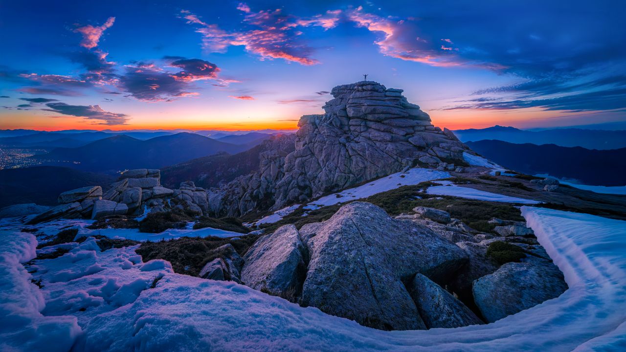 stunning sunset over a rocky mountain peak with snow patches and vibra