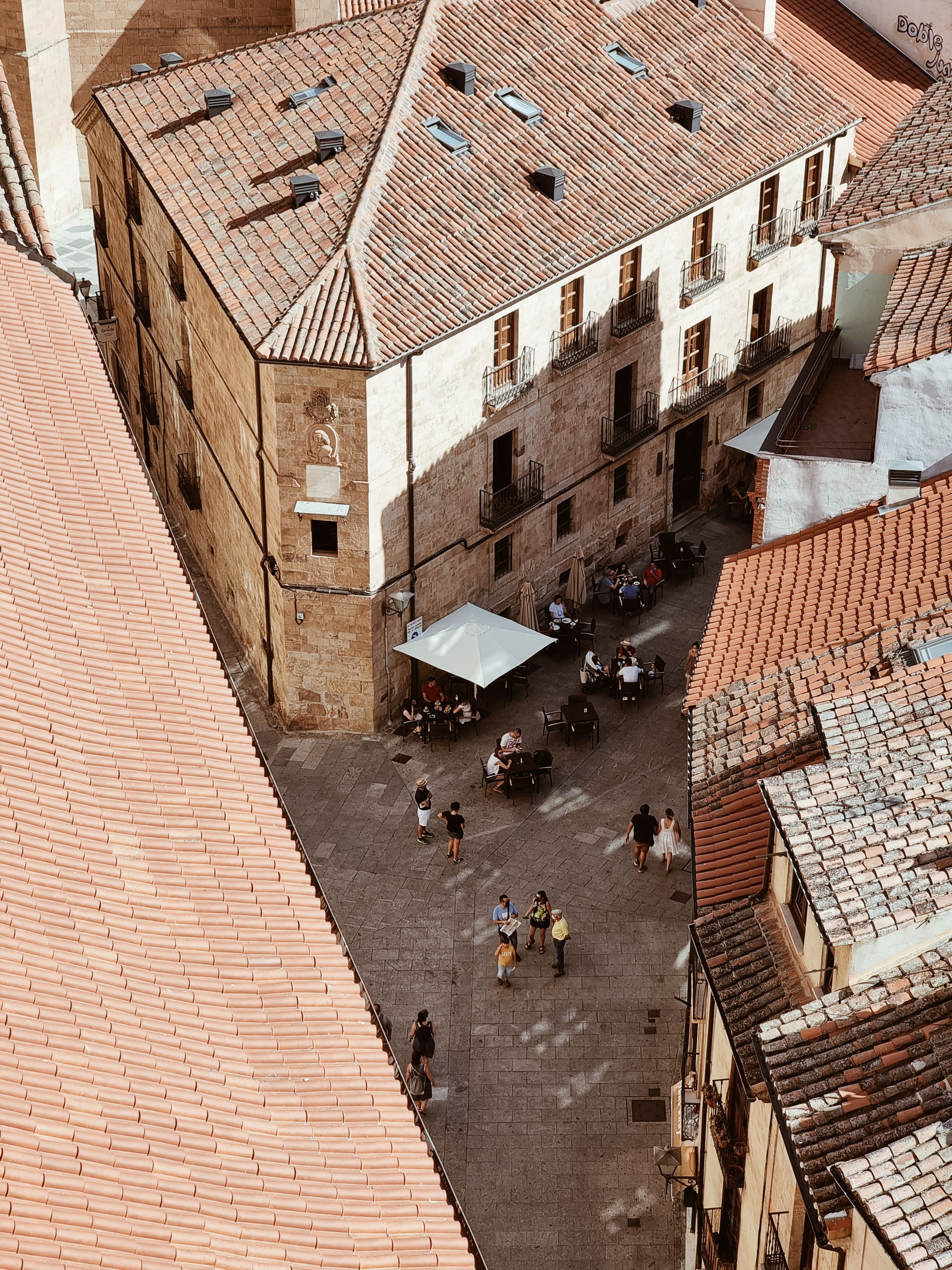 Aerial view of a quaint European courtyard with people at an outdoor cafe.